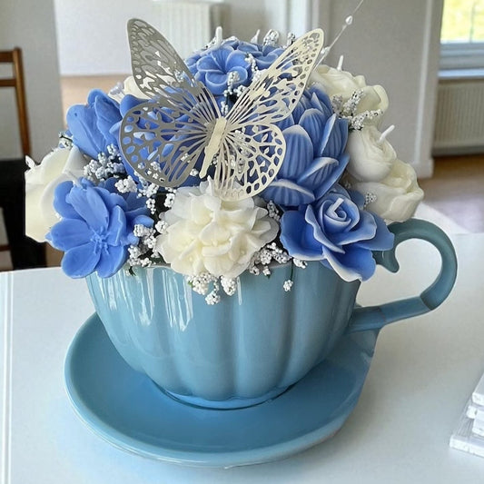 Ramo de flores de cera blancas y azules en taza de cerámica.